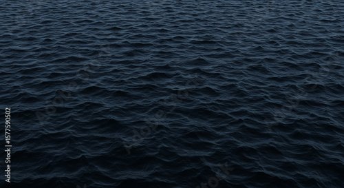 Dark, textured water surface with subtle waves, showing a moody, deep-blue ocean scene.