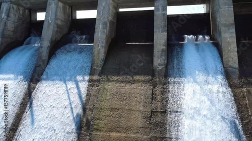 Wallpaper Mural A close-up view of the spillway gates of a hydroelectric dam, releasing a stream of water creating cascades that rise above the structure, providing a panoramic view of its reservoir. Mitis-2 Dam. Torontodigital.ca