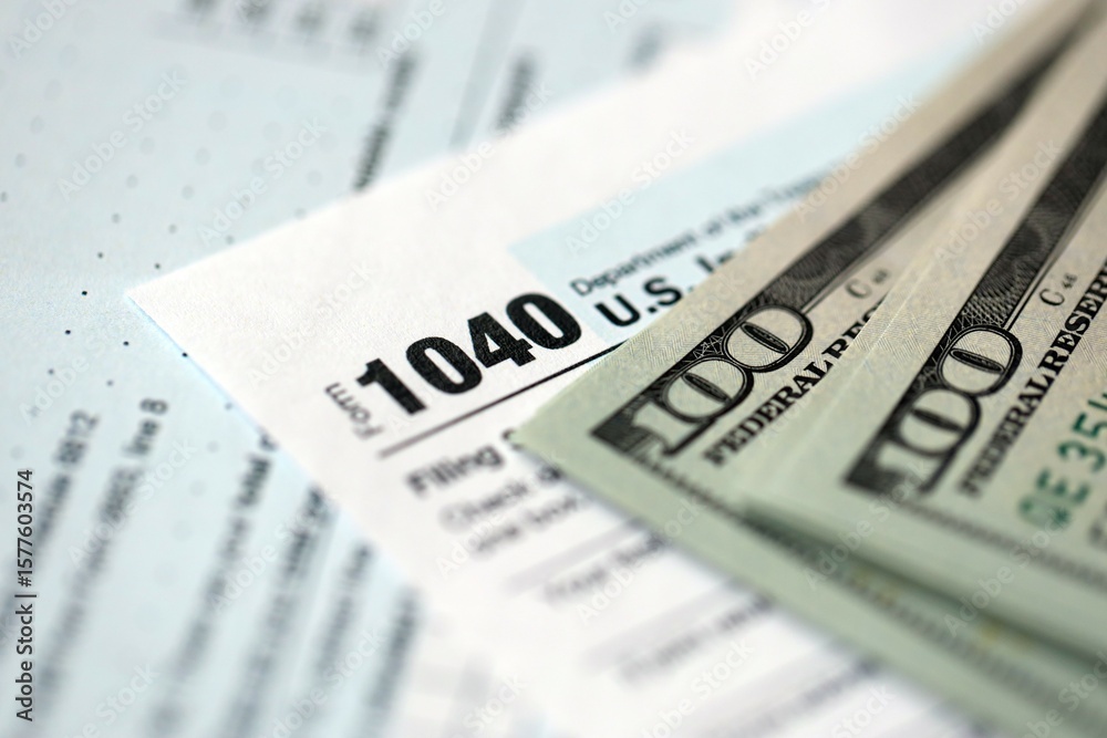 Hundred dollar bills and 1040 individual income tax return form blank close up Hundred dollar bills and 1040 individual income tax return form blank close up