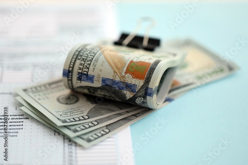 Big amount of United States USD dollar bills banknotes on table with 1040 tax return form photo