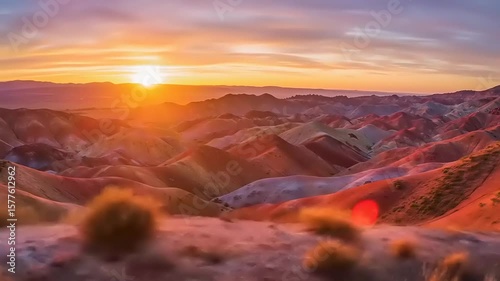 Vibrant sunset over colorful mountains with rolling hills, creating a serene landscape scene