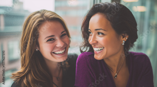 Two young women smiling and laughing together in an office setting