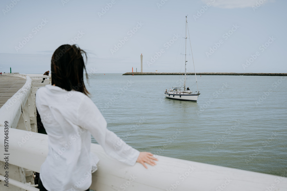 Obraz premium The girl is standing and looking at the passing boat.
