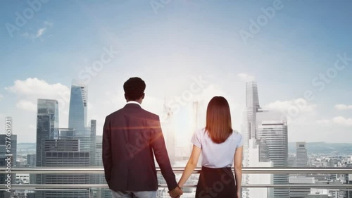 Couple holding hands while admiring a city skyline at sunset, symbolizing love and ambition