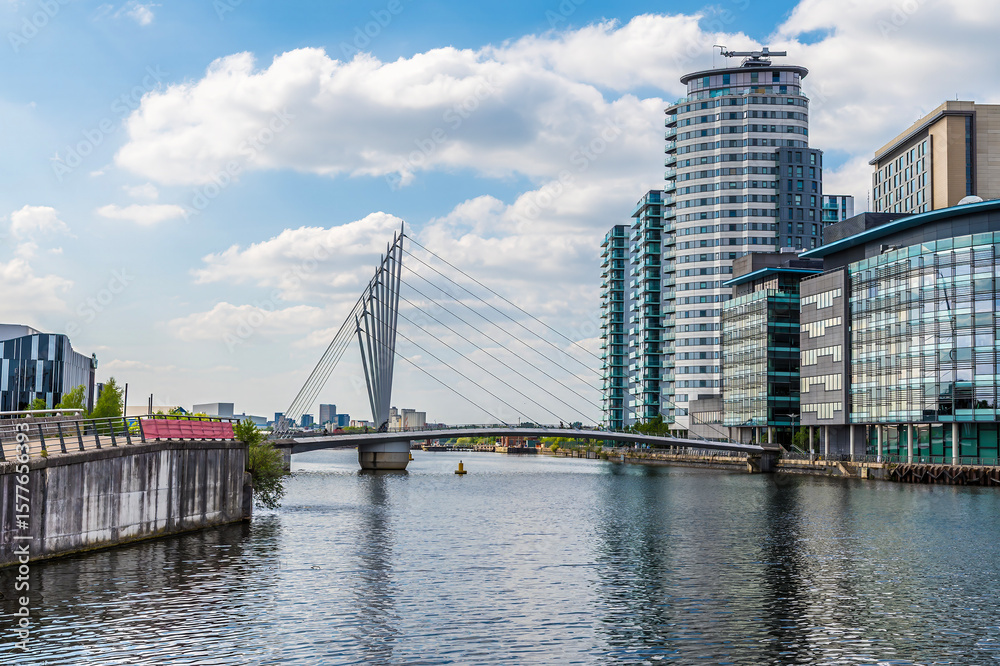 Obraz premium A view up the Manchester ship canal towards a footbridge beside Media City, Manchester,UK in summertime