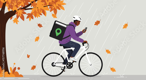 A delivery man on a bicycle is checking his mobile phone while riding through the rain in the autumn season, with falling leaves and a tree in the background
