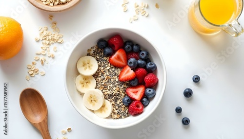HD top-down photography of a healthy breakfast flat lay: a bowl of granola with fresh berries, sliced banana, chia seeds, and almond milk, surrounded by a glass of orange juice, a wooden spoon, and sc