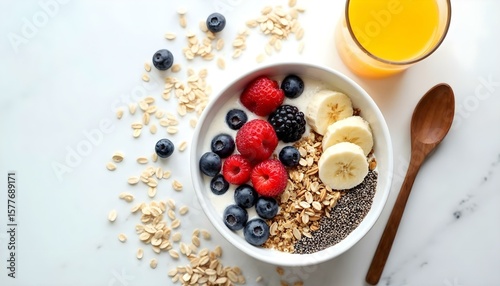 HD top-down photography of a healthy breakfast flat lay: a bowl of granola with fresh berries, sliced banana, chia seeds, and almond milk, surrounded by a glass of orange juice, a wooden spoon, and sc