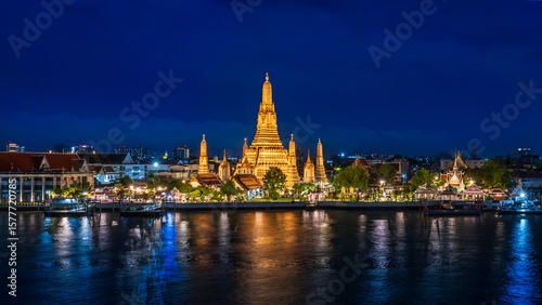 Bangkok wonderful night view of Wat Arun temple beautifully illuminated on the Chao Phraya River with glowing reflections and city lights in the background