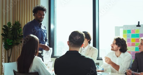 Creative professional presenting mobile UX/UI wireframes to a diverse team during a brainstorming session, promoting collaboration and innovation in a modern office setting.