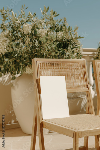 Blank white card resting on a wooden chair outdoors with blooming flowers