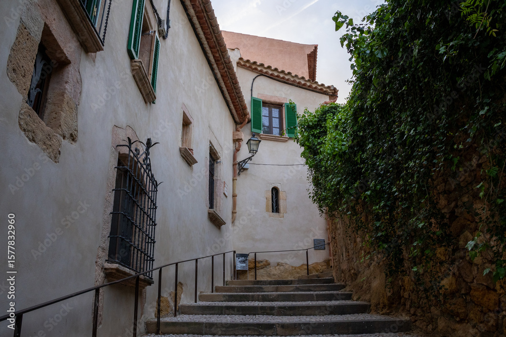 Obraz premium Scenic medieval street in Altafulla, Spain, with colorful facades, stone walls, and vibrant southern charm.