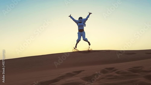 Business woman celebrate victory jumping barefoot on Desert dune at sunset in Dubai