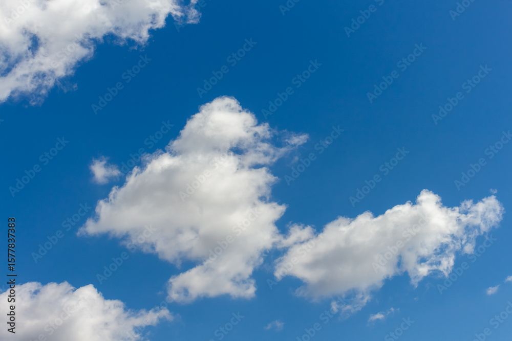 Bright clouds drift across a clear blue sky during midday Bright clouds drift across a clear blue sky during midday