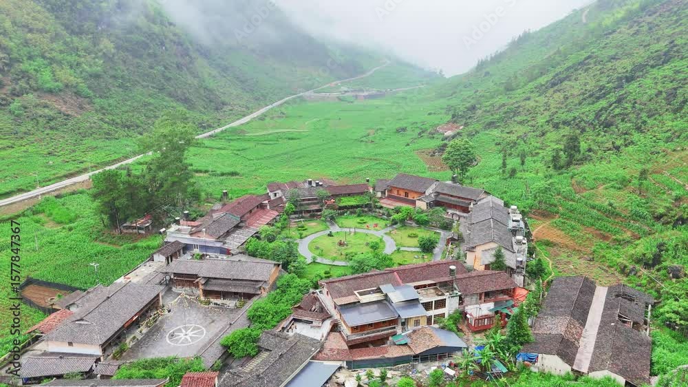 Drone shot of a circular highland village surrounded by lush fields and misty green hills in Vietnam Drone shot of a circular highland village surrounded by lush fields and misty green hills in Vietnam