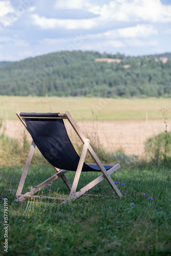 chair on grass with hills and clouds in background 