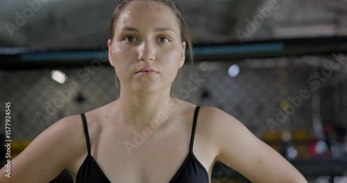 Young white girl athlete resting after training or competition in wrestling or fighting being in gym in octagon cage