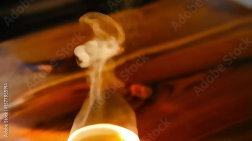 Steaming hot cup of tea on wooden table with sunlight and soft focus