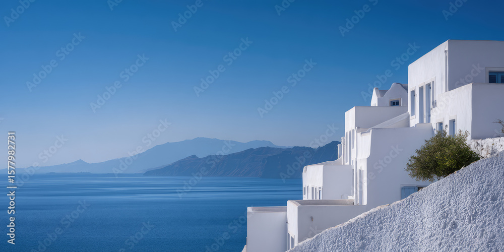 Obraz premium White buildings are perched on a hillside overlooking a tranquil sea and distant mountains. Coastal serenity, architecture, and nature