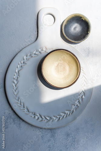 Overhead view of a ceramic board with two ceramic bowls on a  table in sunlight