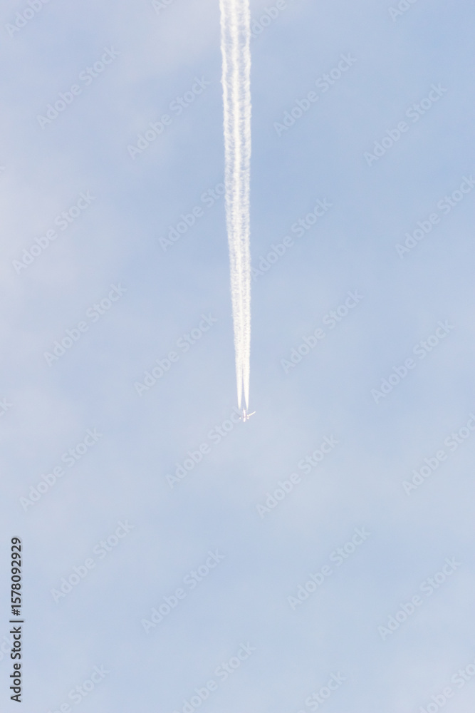 Fototapeta premium Airplane trail in the blue sky with white clouds