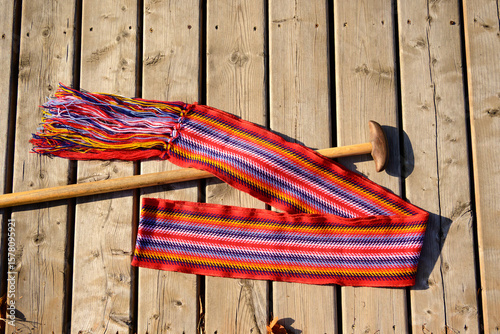 ceinture fléchée (traditional pattern) replica of the woven sash worn by voyageurs during the fur trade shot on wood deck with a wooden canoe paddle shaft room for text
