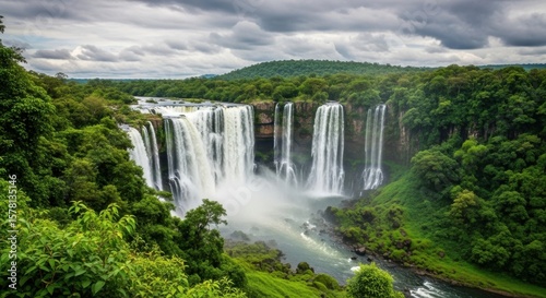 Majestic Waterfall Cascading Through Lush Green Forest Under Dramatic Cloudy Sky