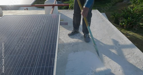 Painter applying a fresh white waterproof coat paint with a roller tool to a roof surface. 