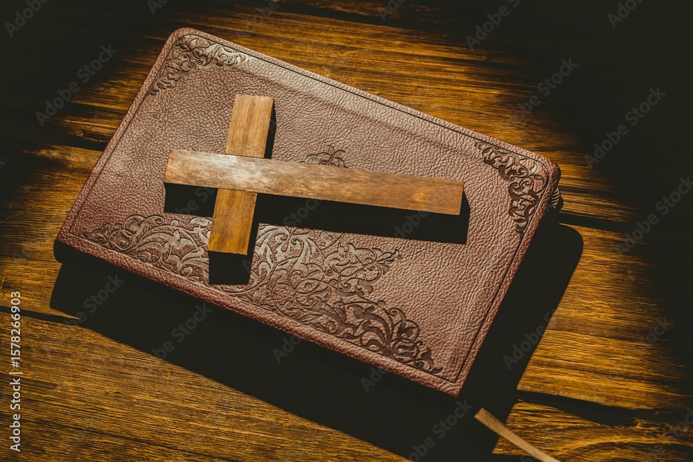 Naklejka premium Wooden cross on bible at desk