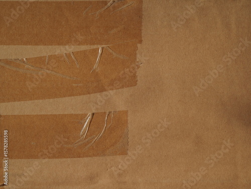 The surface of a kraft brown cardboard box with tape and staples