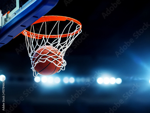 Orange basketball swishing through net with stadium lights hoop scoring