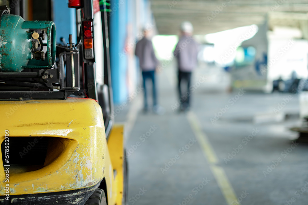 Fototapeta premium Blur Young and senior warehouse workers walk through a loading zone surrounded by cargo trucks. Background shows organized freight lines and operational warehouse flow.
