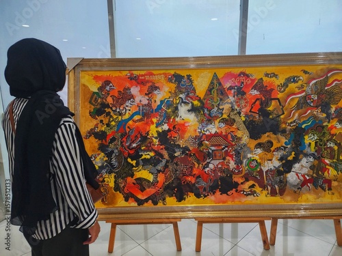 A person observing a vibrant traditional painting in an art gallery