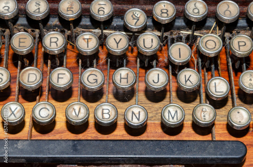 Close up of the keyboard of an old rusty typewriter with cobwebs sitting on a wooden desk