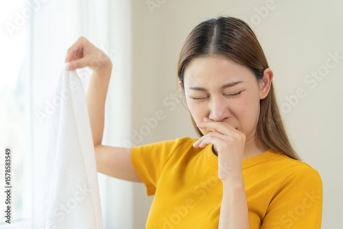 Young people doing laundry smelling for dirty clothes.
