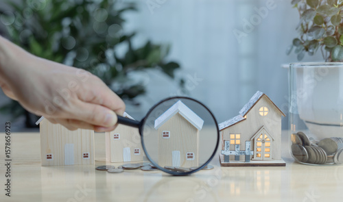 Fotografie Hand holding magnifying glass inspecting house model
