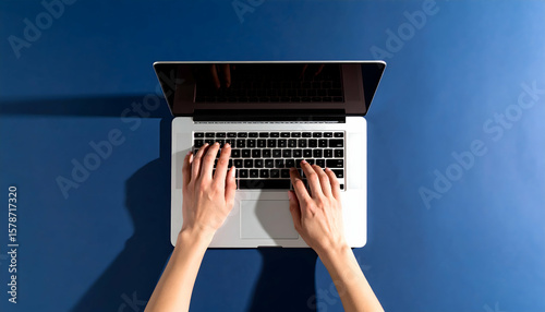 Hands Typing on Modern Laptop Computer Overhead View on Blue Background