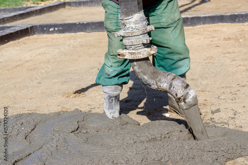 Worker Operating Cement Flow Hose for Construction Site Groundwork