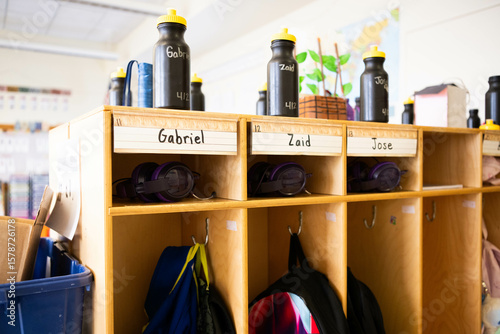 Organized student storage cubbies in elementary school classroom with school supplies and name labels for a diverse set of students, including Zaid, Gabriel, and Jose.
