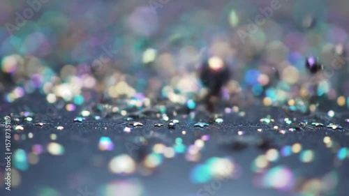 Sparkling iridescent beads falling onto a surface with bokeh background effect