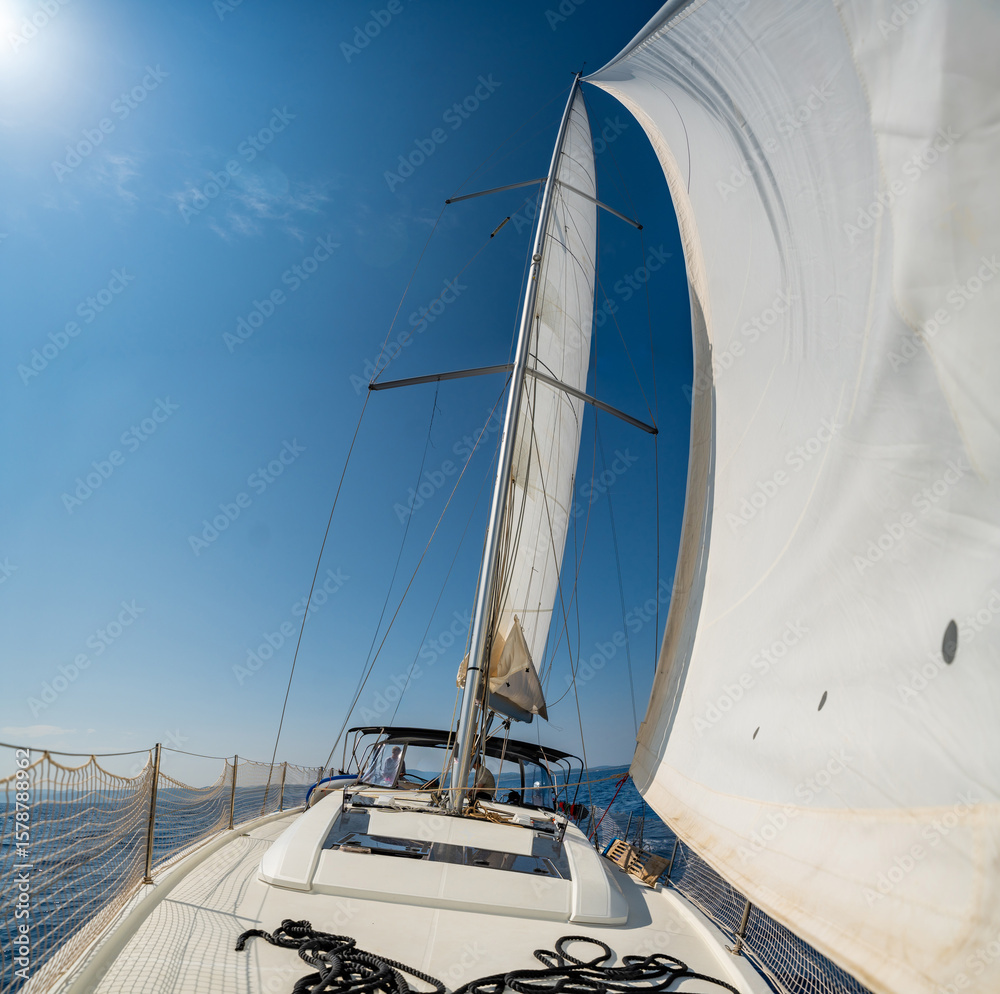 Obraz premium White sails filled with wind, seen from the bow of a sailing yacht near Croatia. Freedom, clean energy, adventure and mindful travel on the open sea.