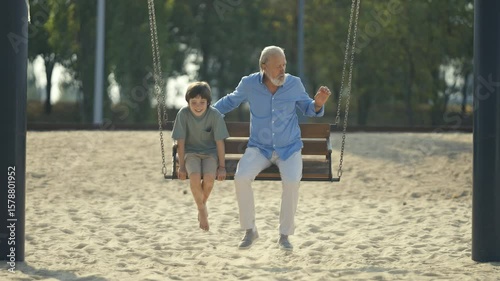A heartwarming scene of a loving grandfather and his excited grandson happily sharing joyful moments on a swing