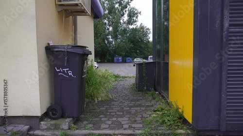 A trash bin in an alley, with a parking lot in the background, offering a glimpse into the urban landscape and everyday life 