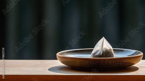 Elegant Geometric Tea Pyramid Resting on a Minimalist Plate Against a Soft Focus Background