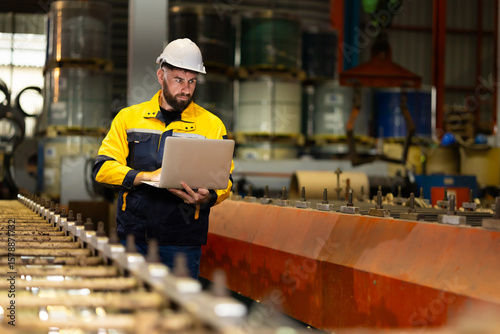 Laptop computer : blue collar working production line : Caucasian man engineer worker working control sheet metal roof tile roll forming machine at metal sheet profiling factory. Industrial production