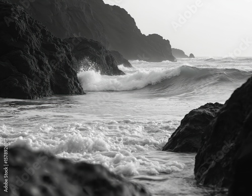 Black and white ocean photo of waves crashing rocks on coastline. Serene coastal landscape with mist fog. Calm sea, nature scenic background for travel, tourism, eco concept.