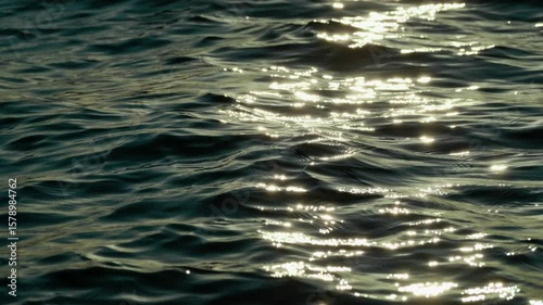 Abstract Close-Up of Sea Waves Glistening Under a Warm Sunset Glow on Ocean Surface