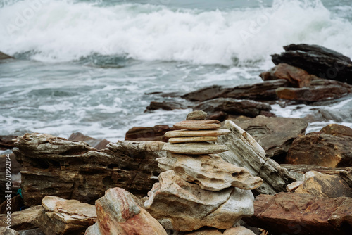 Pebble heap on a beach serene blue sea background zen balanced stones. Close up of rock stack beach in Thailand. Balanced stones on a pebble beach. Nature background concept of balanced rock tower
