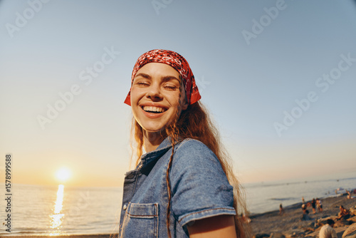 lifestyle woman wearing modern boho-western denim street style smiling at sunset, enjoying relaxed beach atmosphere, film color tone, warm natural light