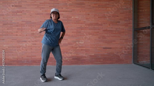 A senior woman stays active and energetic by exercising through aerobic dance. Positive emotion reflects a healthy lifestyle, embracing movement and workout routines to strong in her elderly years